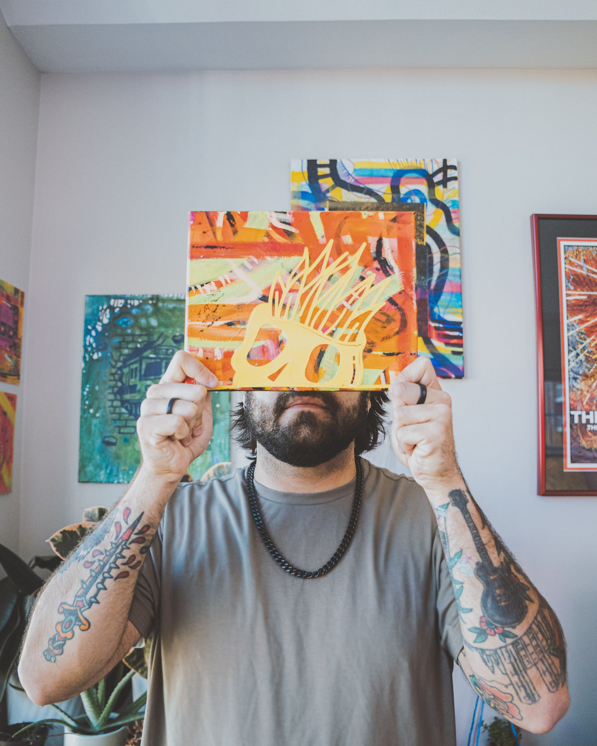 Gonz Veloz in the studio, holding one of his paintings in front of his face